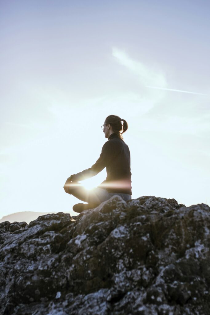 person sitting on rock formation during daytime person sitting on rock formation during daytime