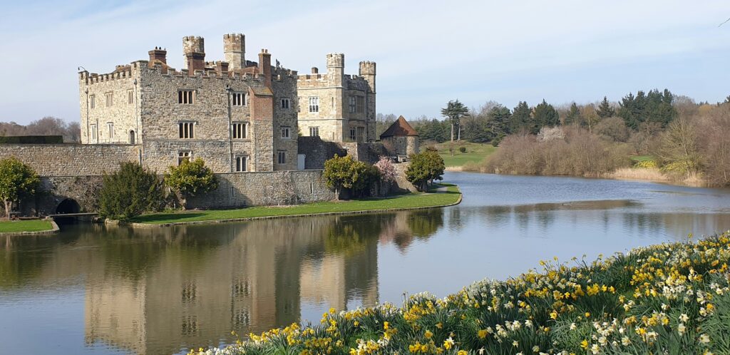a castle sitting on top of a river next to a lush green field a castle sitting on top of a river next to a lush green field
