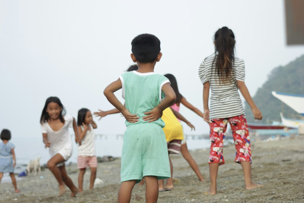 a group of children walking on a beach a group of children walking on a beach
