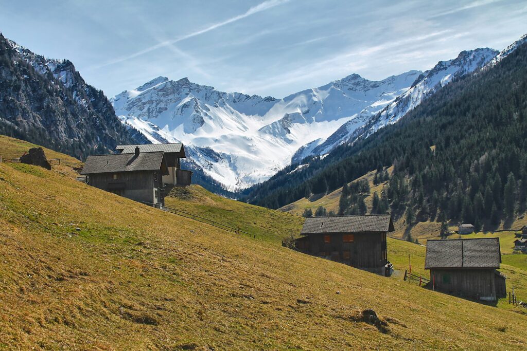 a group of houses sitting on top of a lush green hillside a group of houses sitting on top of a lush green hillside