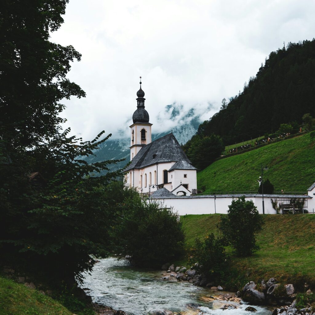 a river running through a lush green hillside next to a church a river running through a lush green hillside next to a church