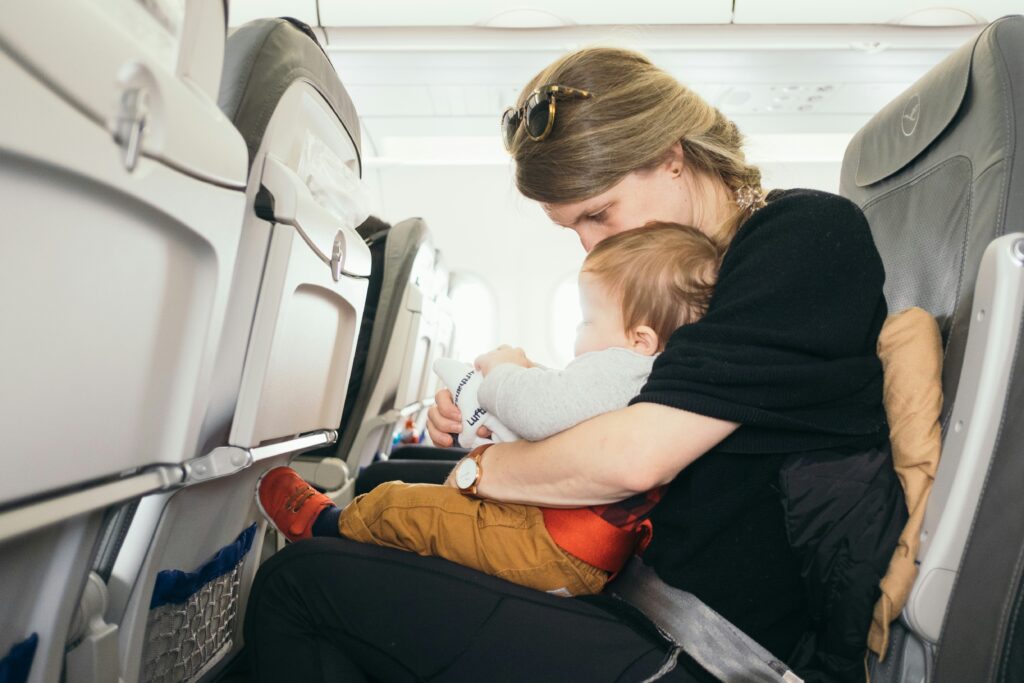 woman carrying baby while sitting on gray seat woman carrying baby while sitting on gray seat