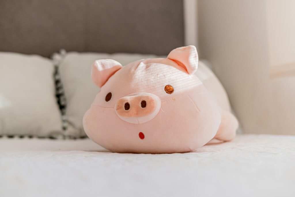 A cute pink pig plush toy on a bed. A cute pink pig plush toy on a bed.