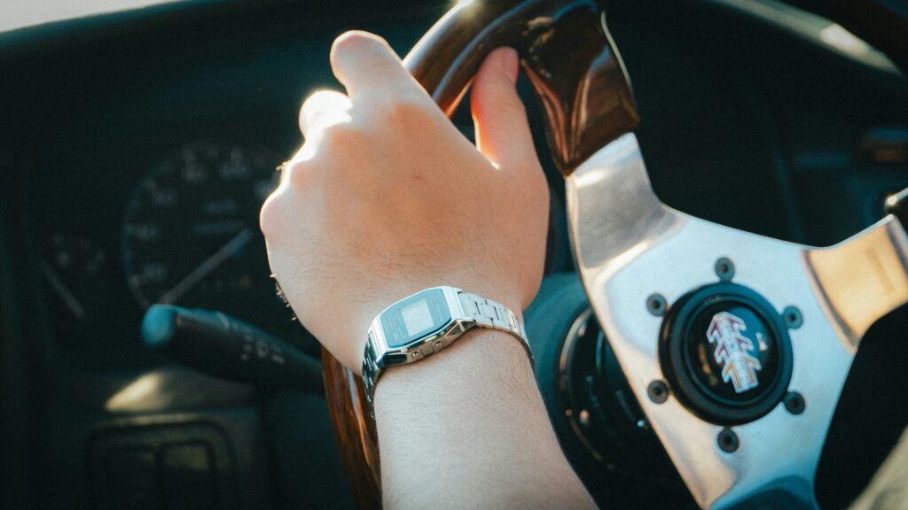Person's hand on the steering wheel of a car.